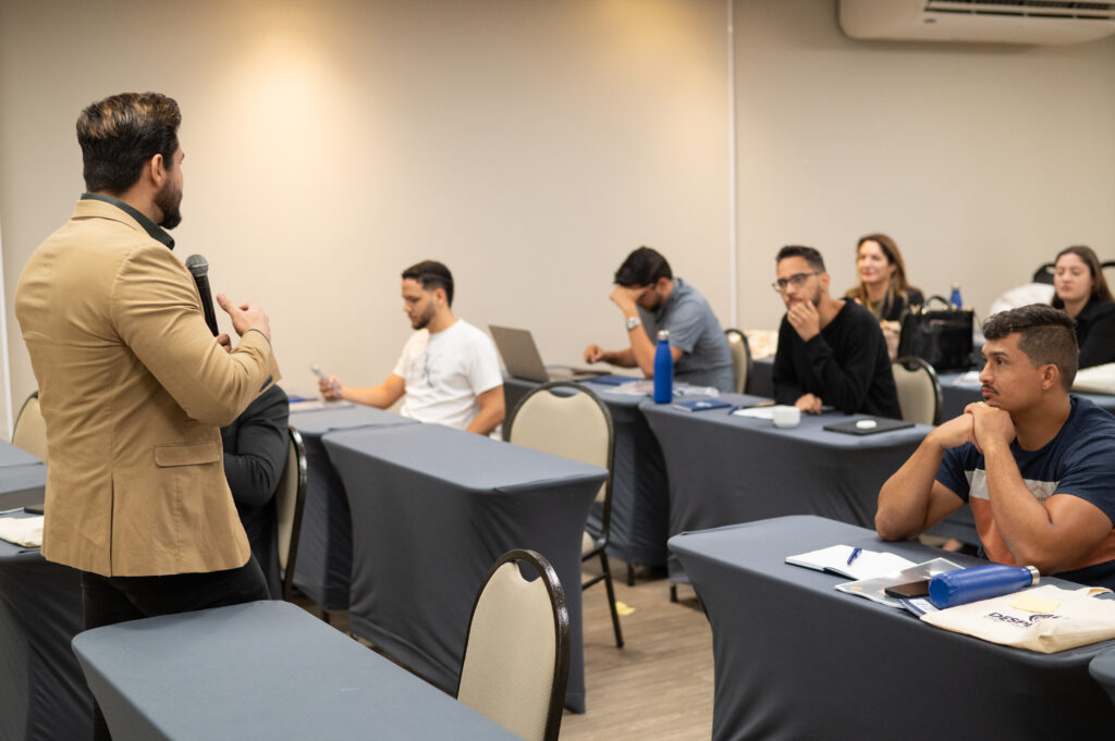 Janderson Santos conduzindo treinamento de vendas em sala com mesas e participantes