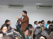 Palestrante de vendas em pé realizando palestra para vendedores