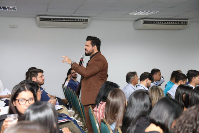 Palestrante de vendas em pé realizando palestra para vendedores