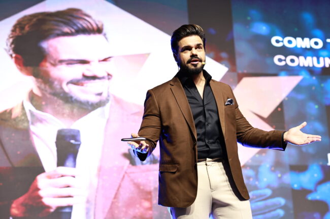 Janderson Santos, o Mago das Vendas, de blazer marrom e microfone na mão durante palestra Janderson Santos, o Mago das Vendas, de blazer marrom e microfone na mão durante palestra de vendas