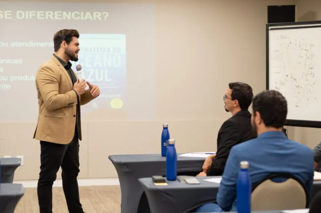 Janderson Santos, de blazer bege, conduzindo o treinamento Despertar Empresarial para Janderson Santos, de blazer bege, conduzindo o treinamento Despertar Empresarial para empresários