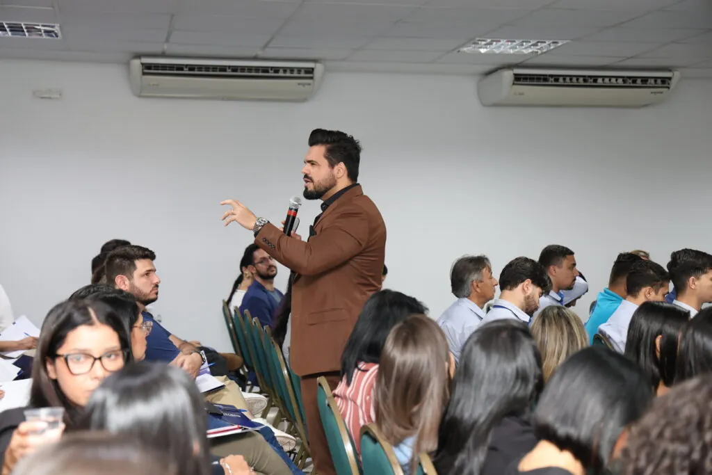 Palestrante de vendas em pé realizando palestra para vendedores